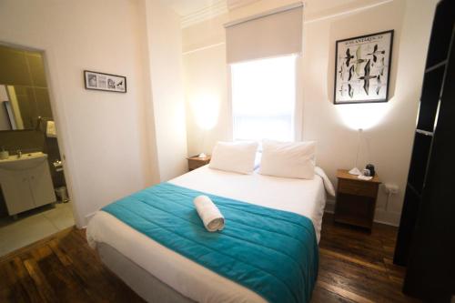 a bedroom with a bed with a blue blanket and a window at HOSTAL BOUTIQUE TERRA ANTARCTICA in Punta Arenas