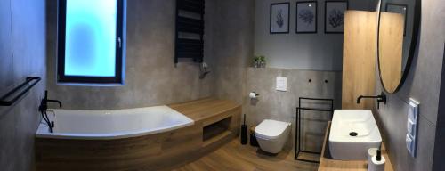 a bathroom with a tub and a toilet and a sink at Slow Life Apartment Mechelinki in Mechelinki
