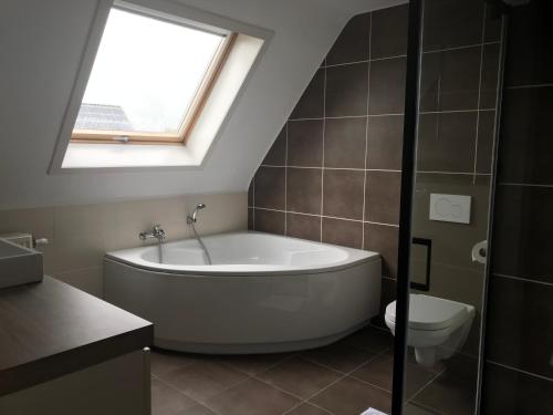 een badkamer met een bad, een toilet en een raam bij Huis Marlin in De Haan