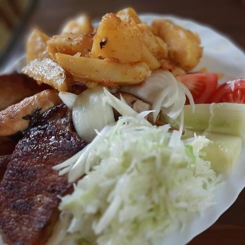 a plate of food with meat and vegetables on a table at Woden apartment in Žabljak