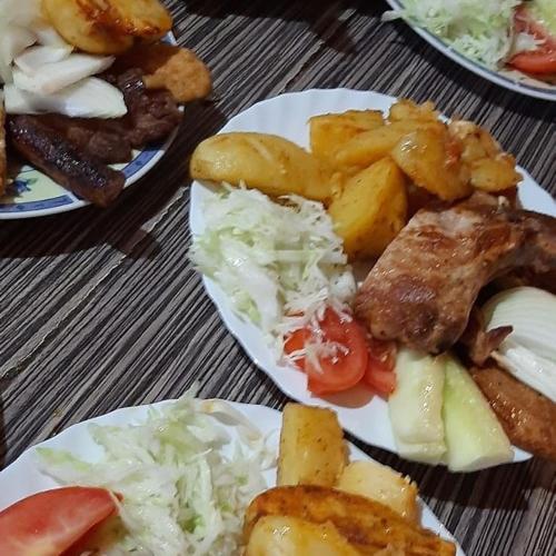 a table with plates of food with meat and vegetables at Woden apartment in Žabljak