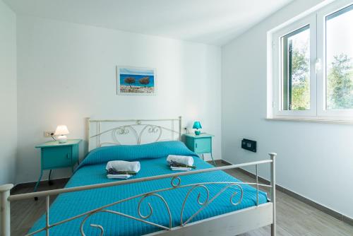 a bedroom with a blue bed and two windows at Apartments Garden in Baška