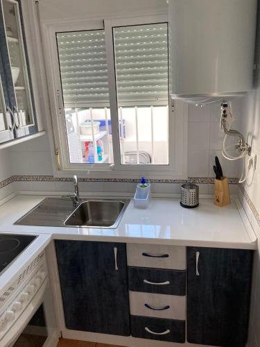 a kitchen with white counters and a sink and two windows at Playa Golf IV in Islantilla