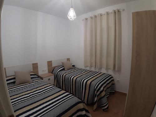 two beds in a room with white walls at Playa Golf IV in Islantilla