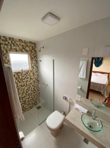 a bathroom with a toilet and a shower and a sink at Cores do Cerrado - chalés e suítes in Goiás