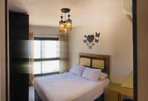 1 dormitorio con 1 cama con lámpara de araña y ventana en بورتوسعيد Porto Said en Port Said