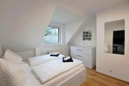 a white bedroom with a bed and a window at Pension Aspen in Železná Ruda