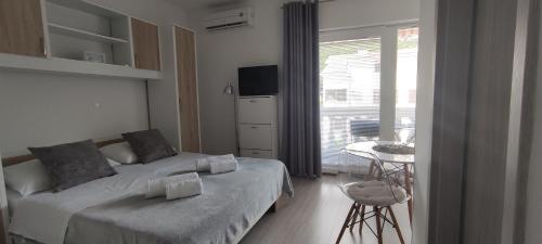 a bedroom with a bed and a table and a window at Apartments M&M in Baška