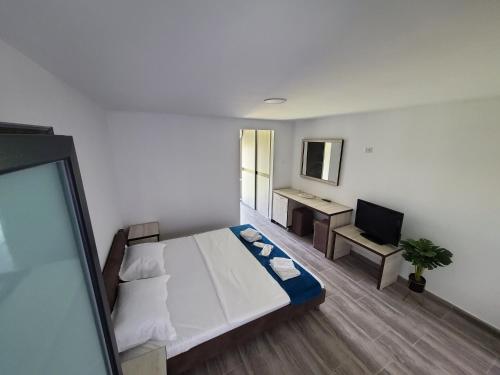 a bedroom with a bed and a desk with a television at Vila Paradis Costinesti in Schitul