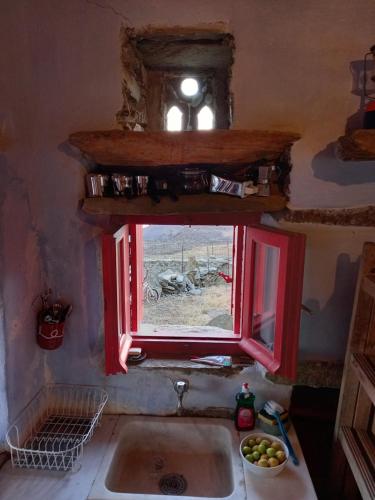 a kitchen with a sink and a red window at Katerina's Sunset in Panormos
