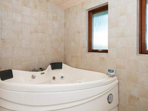 La salle de bains est pourvue d'une baignoire blanche et d'une fenêtre. dans l'établissement 6 person holiday home in Ansager, à Ansager