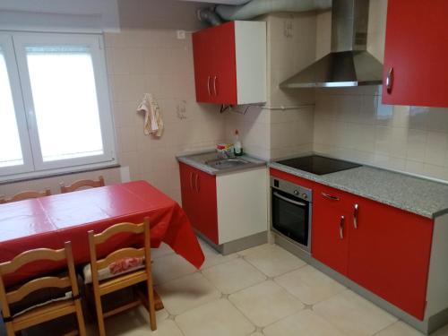 una pequeña cocina con armarios rojos y una mesa y sillas rojas. en Piso Muxía centro, en Muxía