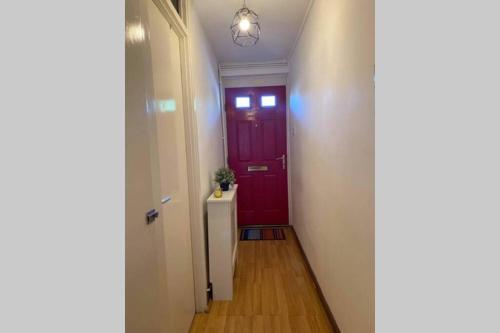 un pasillo con una puerta roja y una pared blanca en Beautiful Large ROOM in London Flat, en Londres