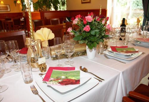 a table with a white table cloth and pink flowers on it at Hotel Korona in Słubice