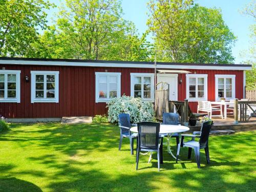 una casa roja con una mesa y sillas en un patio en 5 person holiday home in S LVESBORG, en Sölvesborg