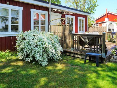 una casa con un banco junto a un arbusto con flores blancas en 5 person holiday home in S LVESBORG, en Sölvesborg