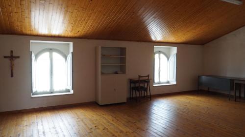 an empty room with two windows and a wooden ceiling at Residenza Pitigliano Gens Petilia - Nuova gestione in Pitigliano