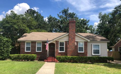 a brick house with a flag in the yard at Dolphina House Pensacola in Pensacola
