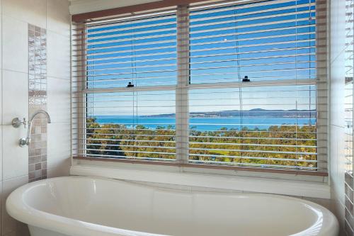 a bath tub in a bathroom with a large window at Whale Cove Circuit in Eden