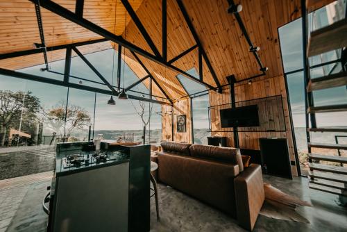 a living room with a couch and a tv and windows at Casas na montanha - Villa Montegrappa in Caxias do Sul