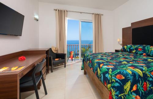 a hotel room with a bed and a desk and a bed and a deskablish at Samsara Cliff Resort in Negril
