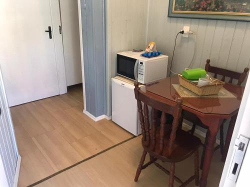 a table with a microwave and a table with a chair at Apartamentos Sulla Collina Centro de Gramado localizado próximo da rua Coberta in Gramado
