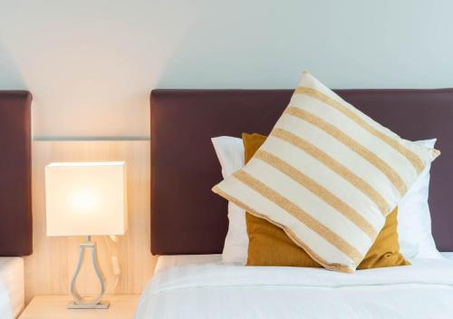 a bed with a pillow and a lamp on it at VSK RESIDENCE - SHA Extra Plus in Lat Krabang