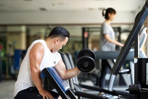 a man lifting a dumbbell in a gym at The Howard Plaza Hotel Taipei in Taipei