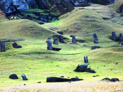 a grassy hill with blue columns in a field at Cabañas Te Maori in Hanga Roa