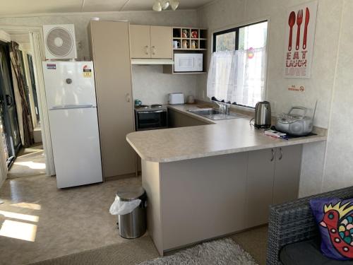 cocina con nevera blanca y encimera en Te Puru B8 - 2 bedroom chalet en Te Puru