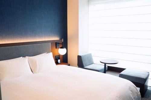 a bedroom with a white bed and a chair and a window at Hotel The M's Kyoto in Kyoto