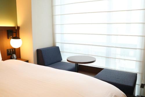 a bedroom with a bed and two chairs and a table at Hotel The M's Kyoto in Kyoto