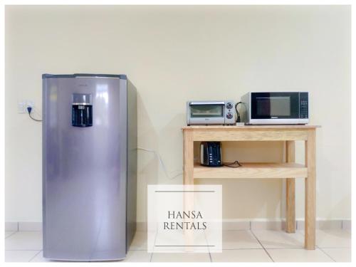 a refrigerator next to a table with a microwave at Casa Hansa alojamientos vacacionales in Puerto Vallarta