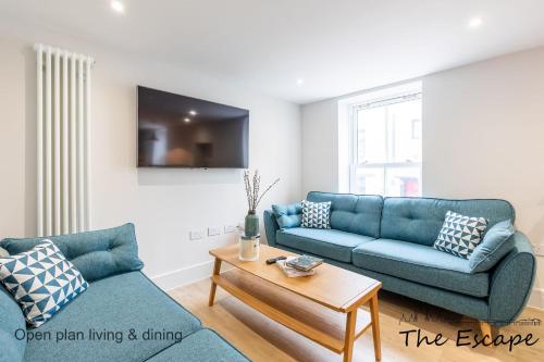 a living room with two blue couches and a table at The Escape; the ideal getaway on Brighton seafront in Brighton & Hove