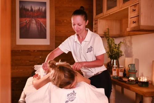 a woman in a salon cutting a mans hair at Apartamenty u Harrego BOUTIQUE SPA in Kudowa-Zdrój