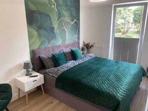 a bedroom with a bed with a green comforter at Apartament Sosnowa 4 in Mielno