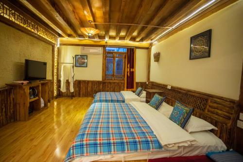a bedroom with two beds and a television in it at Shangri-La King Gesar Guesthouse in Shangri-La