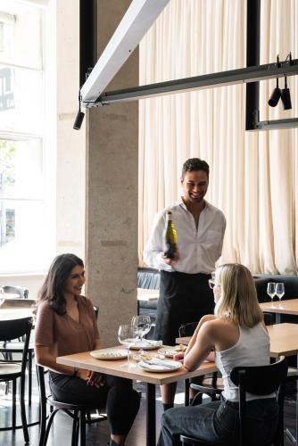 a man standing at a table with a bottle of wine at Alex Hotel in Perth