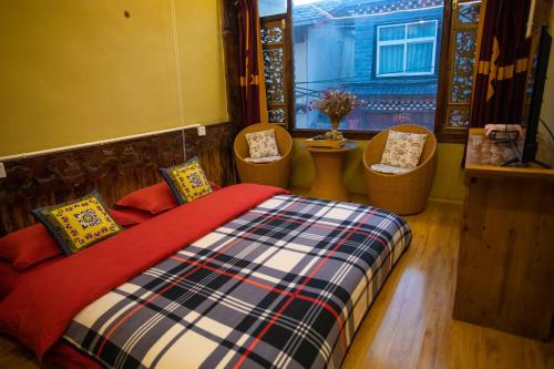 a bedroom with a bed and two chairs and a window at Shangri-La King Gesar Guesthouse in Shangri-La