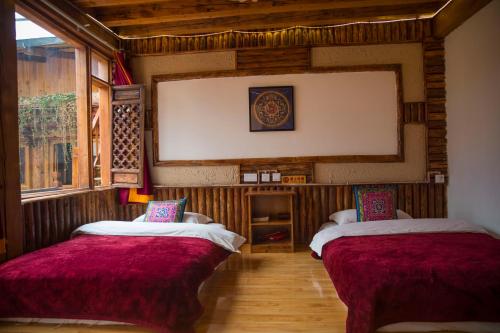 two beds in a room with wooden walls at Shangri-La King Gesar Guesthouse in Shangri-La