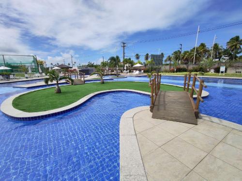 a large swimming pool with a wooden bridge in a resort at Porto de Galinhas | Muro Alto 116B in Porto De Galinhas