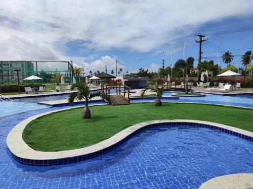 a swimming pool with a lawn with palm trees in it at Porto de Galinhas | Muro Alto 116B in Porto De Galinhas
