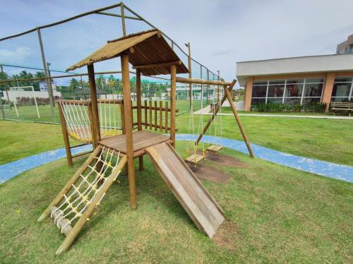 a wooden playground with a slide in a field at Porto de Galinhas | Muro Alto 116B in Porto De Galinhas