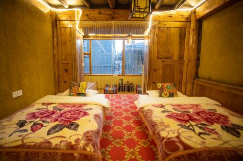 a room with two beds with flowers on them at Shangri-La King Gesar Guesthouse in Shangri-La