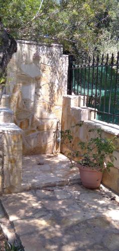 a stone wall with a potted plant next to a fence at Geranium Villa by the sea in Kineta