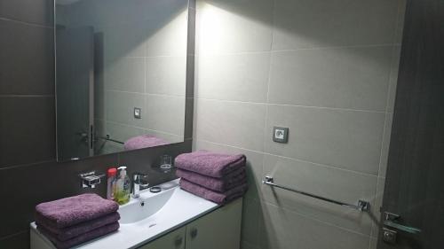 a bathroom with a sink and a mirror and purple towels at Artistica Suite - Central Park in Mohammedia