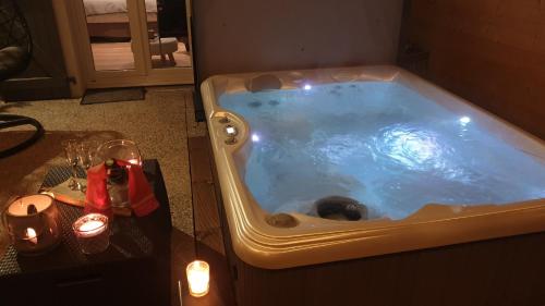a jacuzzi tub in a room with a table and candles at AU NID COSY D'ISA A GERARDMER VOSGES - Spas privatifs in Gérardmer