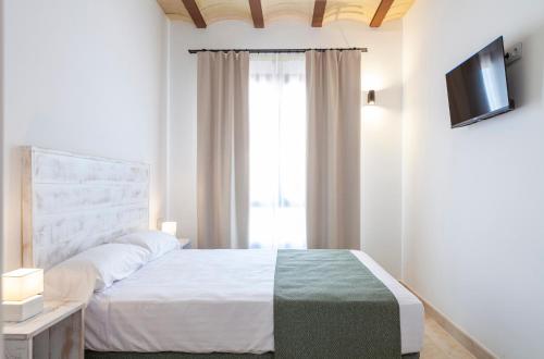 a bedroom with a white bed and a television at Ad Hoc Vitae Retreats & Health Only Adults in Beniarbeig