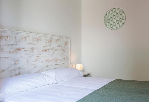 a bedroom with a white bed with a wooden headboard at Ad Hoc Vitae Retreats & Health Only Adults in Beniarbeig