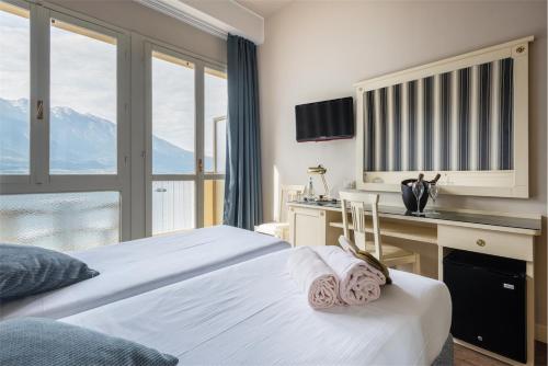 a bedroom with a bed and a desk with a view at Hotel Splendid Palace in Limone sul Garda